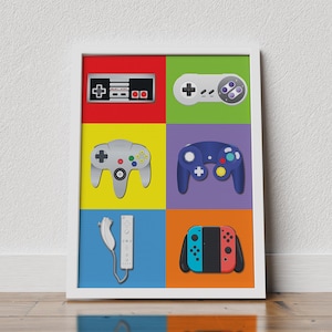 Puede incluir: Una impresión enmarcada con seis mandos de videojuegos diferentes, cada uno en un fondo de color diferente. Los mandos son de la NES, Super Nintendo, Nintendo 64, GameCube, Wii y Nintendo Switch.