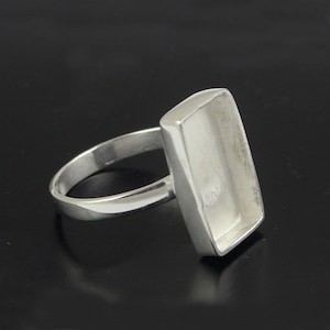 May include: Silver ring with a rectangular bezel setting. The bezel is empty and ready to be filled with a stone or other embellishment.