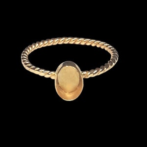 Puede incluir: Un anillo de oro con una banda trenzada y un engaste redondo y liso.