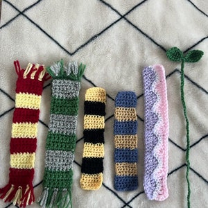 May include: Six crocheted bookmarks, including a green, gray, and yellow striped bookmark, a yellow and black striped bookmark, a blue and gold striped bookmark, a pink and white bookmark, and a green stem with two green leaves.