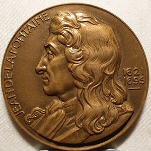 May include: A bronze medal with a profile portrait of Jean de La Fontaine, a French poet and fabulist. The medal is inscribed "JEAN DE LA FONTAINE" and "1621 1695".