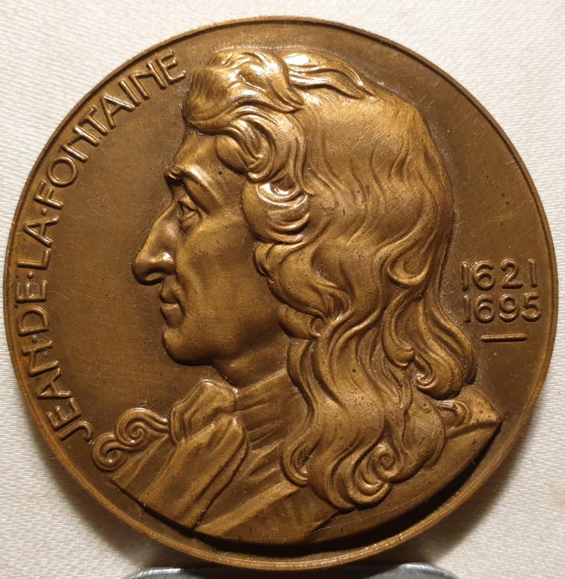 May include: A bronze medal with a profile portrait of Jean de La Fontaine, a French poet and fabulist. The medal is inscribed "JEAN DE LA FONTAINE" and "1621 1695".