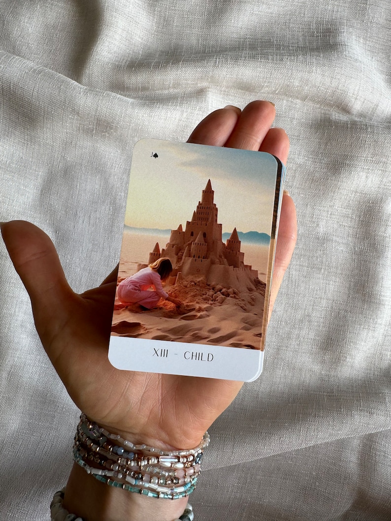 May include: A tarot card with a sandcastle and a child building it on a beach. The card is titled "XIII - CHILD".