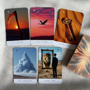 May include: Five tarot cards with different imagery. The cards are laid out in a row, with the top card showing a key in the sand, the second card showing a stork flying in a sunset sky, the third card showing a scythe against a sunset sky, the fourth card showing a mountain with clouds, and the fifth card showing a man standing in front of a mirror with a lion reflected in it. The cards are labeled with their corresponding numbers and names: X - Scythe, XVII - Stork, XXXVIII - Key, XXI - Mountain, and XXXVIII - Man.