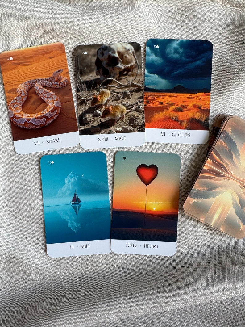 May include: Five tarot cards with colorful images and text. The cards are laid out in a row on a beige fabric surface. The cards are labeled with Roman numerals and the names of the cards: VII - Snake, XXIII - Mice, VI - Clouds, III - Ship, XXIV - Heart.