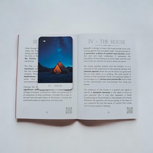 May include: A tarot card with a picture of a tent under a starry sky. The card is titled "House" and the text below reads "Beneath a canopy of stars, the House stands warm and inviting against the cool desert night. This glowing tent is a sanctuary, a place of comfort and security amidst the vast and open wilderness. It represents the foundation of your being, your home base, and the core from which you venture out and to which you return."