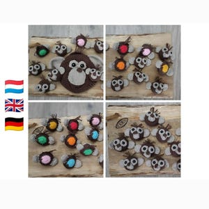 May include: A collection of small, crocheted monkey-themed appliques in various colors. Each piece features a brown face with light tan accents, dark eyes, and a small tuft of hair. The appliques are arranged in groups, showcasing different colored centers.