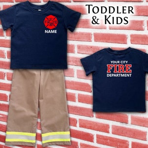 May include: A navy blue toddler firefighter outfit, including a short-sleeved shirt with a red and white fire department emblem and the word "NAME", and tan pants with reflective yellow stripes. The back of the shirt says "YOUR CITY FIRE DEPARTMENT".