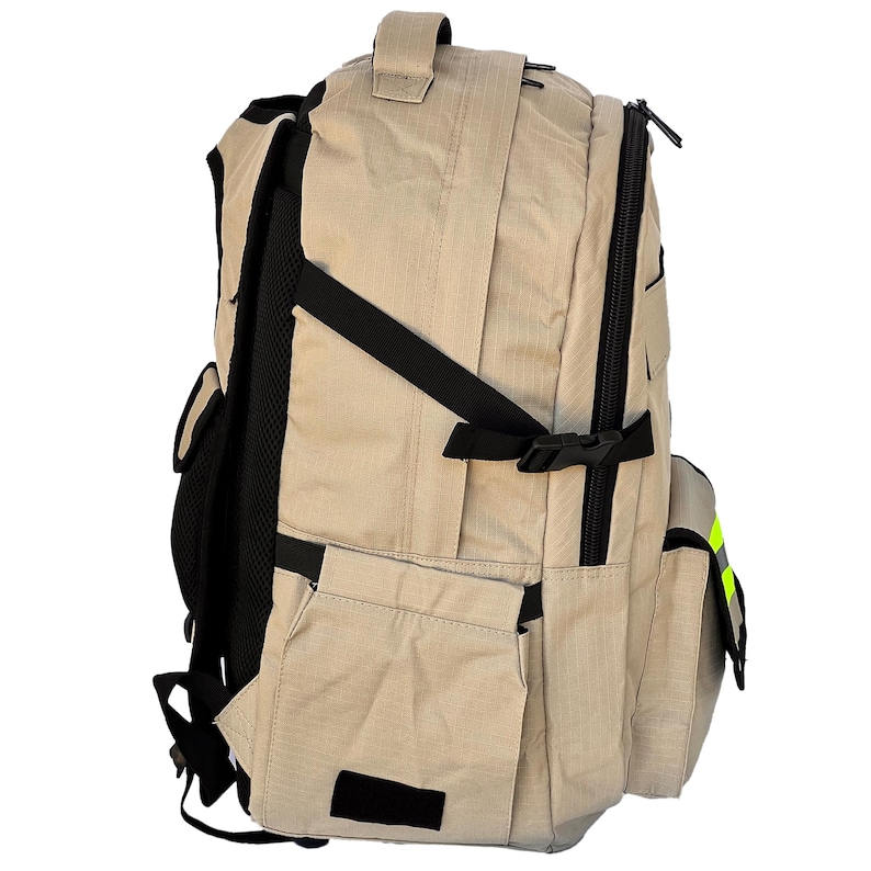 K&ouml;nnte beinhalten: Beigefarbener Rucksack mit schwarzen Riemen und Akzenten. Er verf&uuml;gt &uuml;ber mehrere Taschen, einen oberen Griff und ein Hauptfach mit Rei&szlig;verschluss. Der Rucksack hat ein gepolstertes R&uuml;ckenteil und verstellbare Schultergurte. Ein kleiner, reflektierender gelber Streifen ist sichtbar.