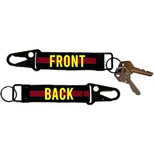 May include: Black keychains with red stripes and the words "FRONT" and "BACK" in yellow. Each keychain has a black clasp and a metal ring. A set of keys is attached to one of the keychains.