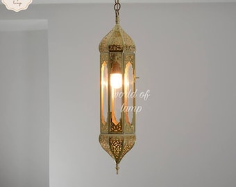 May include: A gold metal pendant light fixture with intricate cutouts and a clear glass shade. The light is hanging from a chain.