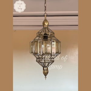 May include: A gold-toned metal and glass pendant light fixture with a geometric design. The light fixture is hanging from a chain.