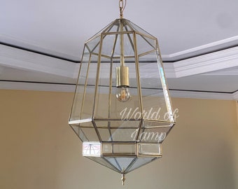 May include: A gold-toned, geometric glass pendant light fixture with a single light bulb hanging from a chain. The light fixture is suspended from a white ceiling.