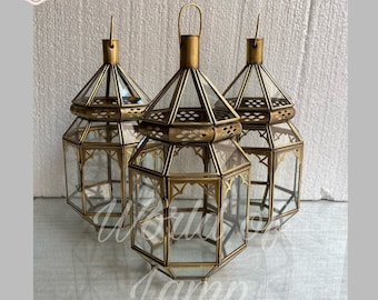 May include: Three gold metal lanterns with clear glass panels. The lanterns have a geometric design and are arranged in a triangular shape.