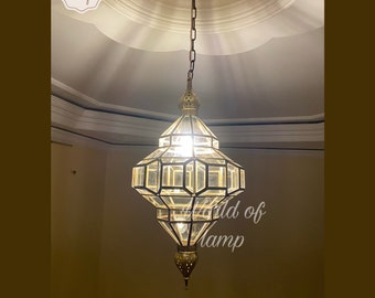 May include: A gold metal pendant light fixture with a clear glass shade. The shade is geometric in shape and has a diamond pattern. The light is hanging from a chain.