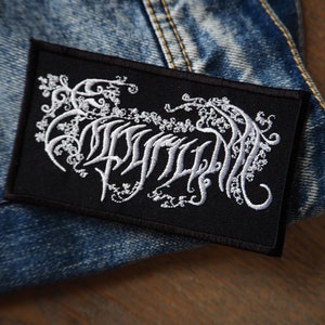 Könnte beinhalten: Schwarzer gestickter Patch mit einem weißen stilisierten Logo, das "DRUID" lautet
