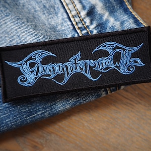 May include: A black embroidered patch with the word "FUNERAL" in blue lettering. The patch is on a blue denim background.