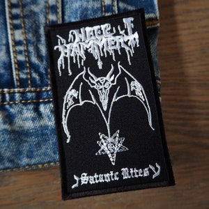 Puede incluir: Parche bordado en blanco y negro con el texto "Hellhammer" y "Satanic Rites" en una fuente gótica. Un demonio alado con cabeza de calavera se encuentra en el centro del parche.