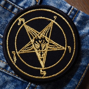 Könnte beinhalten: Ein gestickter schwarzer und goldener Aufnäher mit einem Pentagramm, in dem sich ein Ziegenkopf befindet. Das Pentagramm ist von einem Kreis umgeben.