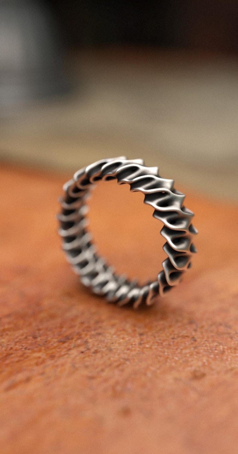 Handcrafted 925 silver wave pattern ring with geometric design and sculptural details on wooden surface