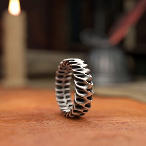 Contemporary style ripple ring in matte sterling silver with architectural wave pattern