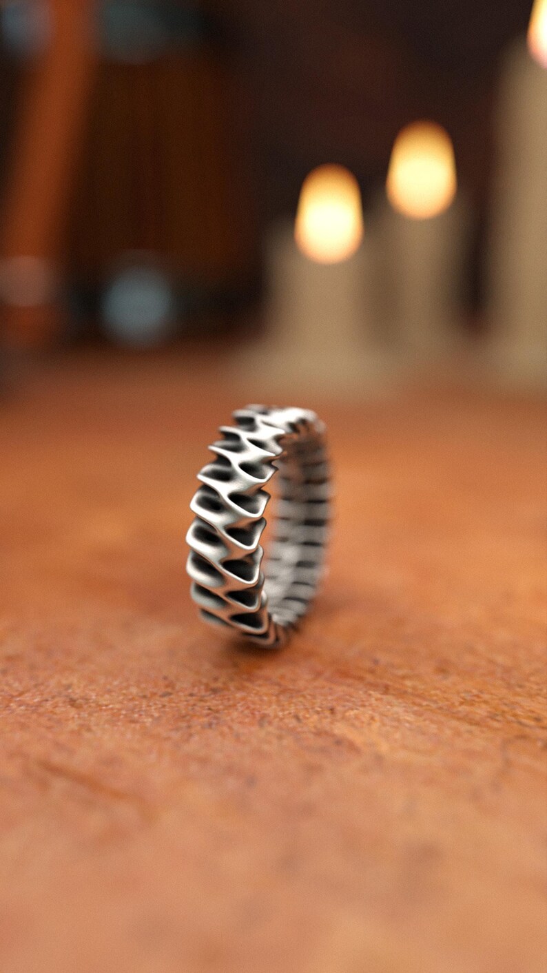 Unisex sterling silver band ring with geometric wave design captured in warm candlelight setting