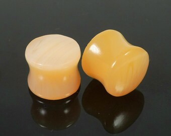 May include: Two pairs of ear gauges, one pair is a light peach color and the other pair is a darker peach color.