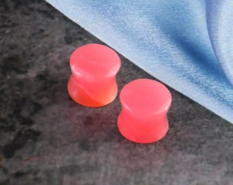 May include: Two pink and white swirl acrylic ear gauges. The gauges are round and have a smooth, polished finish.