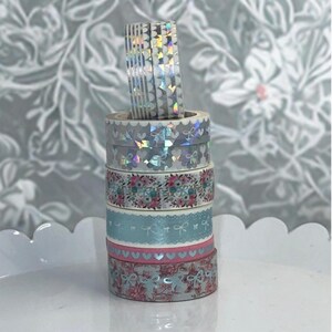 May include: A set of three ceramic mugs with a speckled, matte finish. The mugs are in shades of cream, light gray, and dark gray. Each mug has a simple, modern design and a rounded handle.