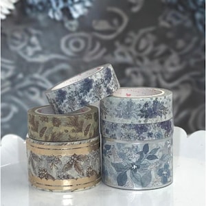 May include: A set of three ceramic mugs with a speckled, matte finish. Each mug features a different color: light blue, cream, and gray. The mugs have a simple, modern design and a comfortable handle.