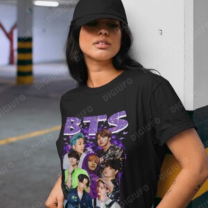 May include: A black t-shirt with a purple and white graphic of the band BTS. The graphic features the band members in a collage style with butterflies and a purple background.