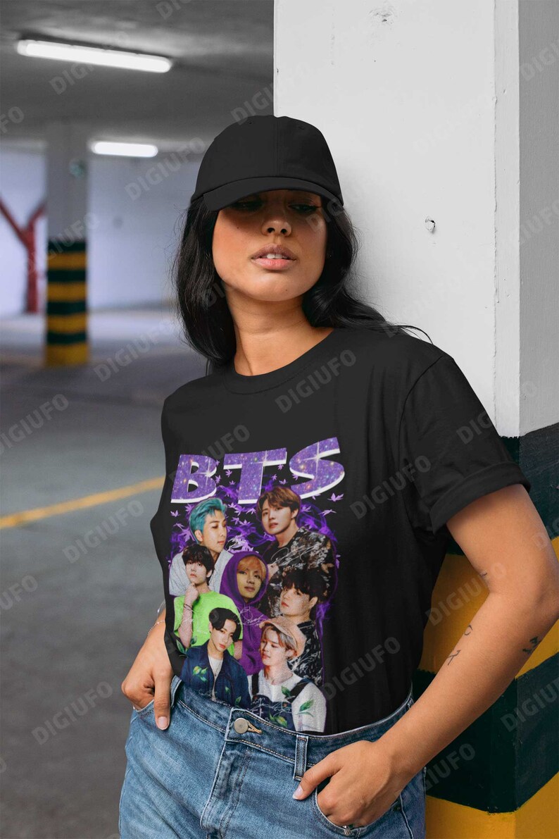 May include: A black t-shirt with a purple and white graphic of the band BTS. The graphic features the band members in a collage style with butterflies and a purple background.
