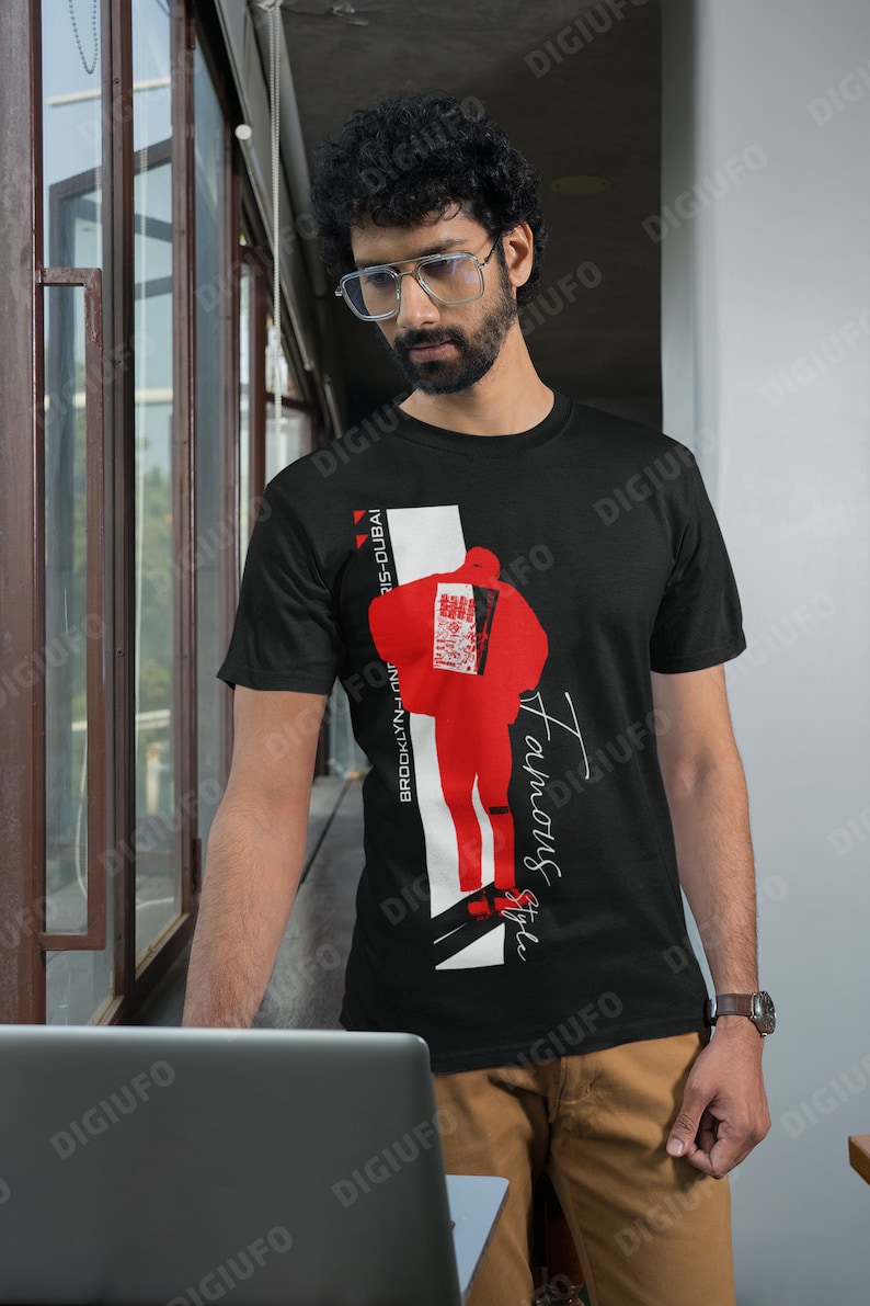 May include: Black t-shirt with a red and white graphic design. The design includes a stylized figure, the words "Famous Style", and the text "Brooklyn-London-Paris-Dubai". The shirt is worn by a person.