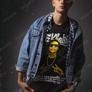 May include: A black t-shirt with a graphic of Wiz Khalifa wearing sunglasses and a gold chain. The shirt also has the text "Khalifa" and the quote "Everyone is born beautiful, some people just let the world turn them into something ugly."