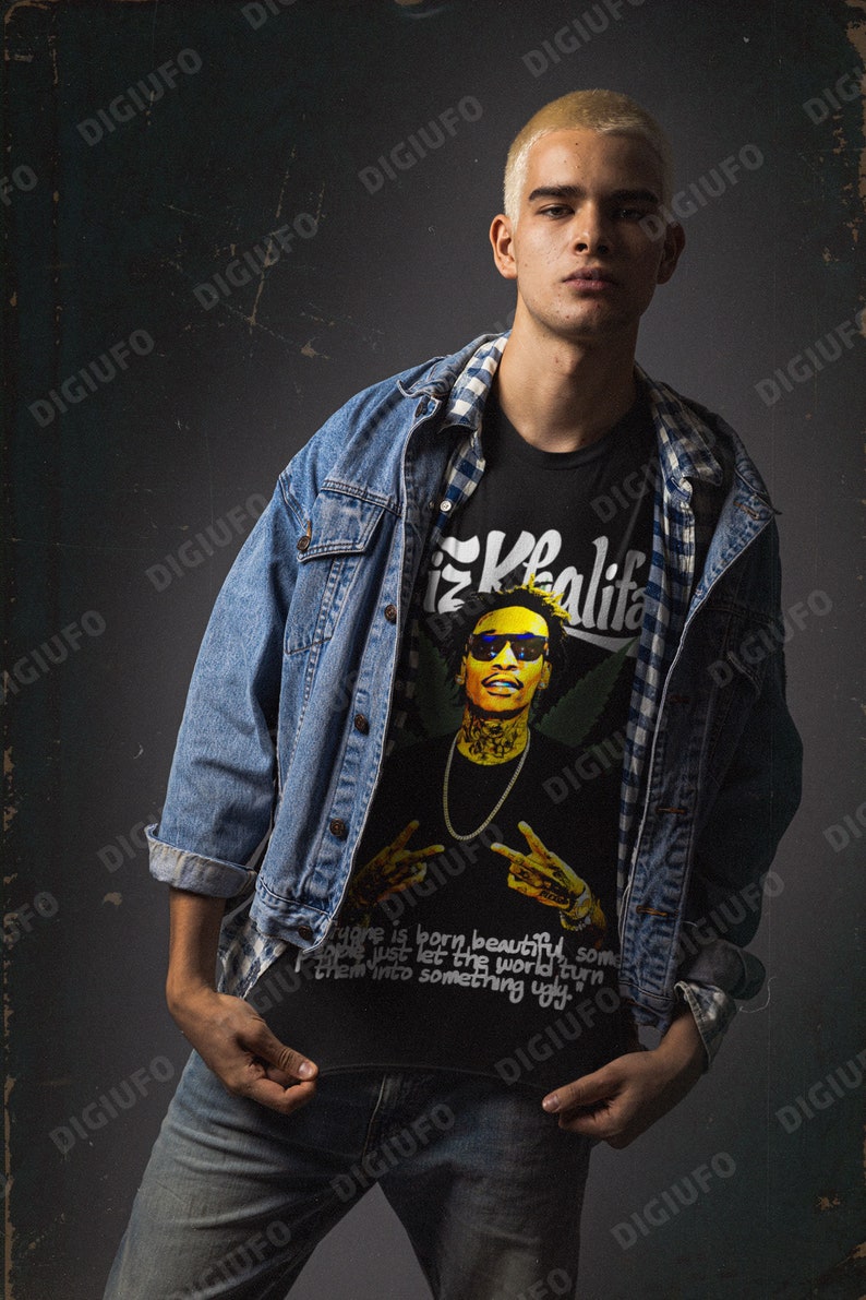 May include: A black t-shirt with a graphic of Wiz Khalifa wearing sunglasses and a gold chain. The shirt also has the text "Khalifa" and the quote "Everyone is born beautiful, some people just let the world turn them into something ugly."