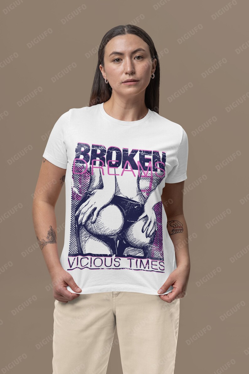 May include: White t-shirt with a graphic design featuring the text "BROKEN DREAMS" and "VICIOUS TIMES" in a distressed font. The design includes a stylized illustration in shades of purple and blue.