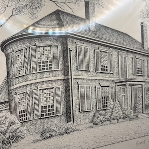 May include: Black and white pen and ink drawing of a large brick house with multiple windows, shutters, and a curved section. The house has a dark roof and is surrounded by trees and bushes. The artist's signature is in the bottom right corner.