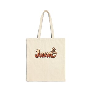 May include: A cream-coloured canvas tote bag featuring a graphic print in the centre. The design displays the word Java in a stylised, layered brown font, with the letter a replaced by a steaming coffee cup illustration in shades of brown.