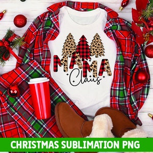 May include: White t-shirt with a Christmas design featuring three trees. The trees are decorated with red and black buffalo plaid and leopard print. The text "Mama Claus" is written in black with a buffalo plaid background.