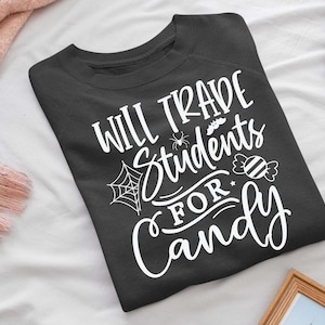 May include: A dark gray sweatshirt with the text "Will trade students for candy" in white lettering. The text is surrounded by a spider web, a spider, and a candy cane.