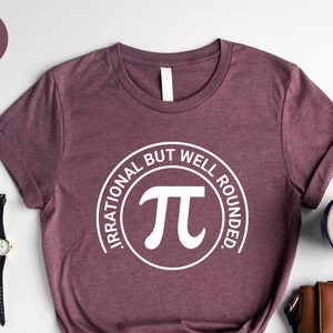 May include: Heather maroon t-shirt with a white circle graphic that says "Irrational but well rounded" and has a white pi symbol inside the circle.