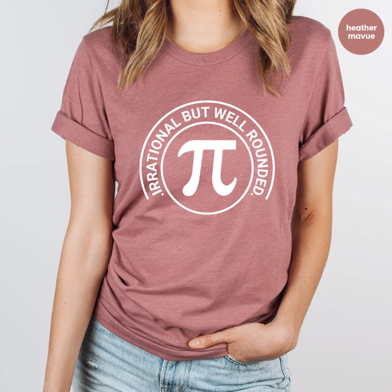 May include: A heather mauve t-shirt with a white circle graphic featuring the mathematical symbol pi and the text "Irrational But Well Rounded."