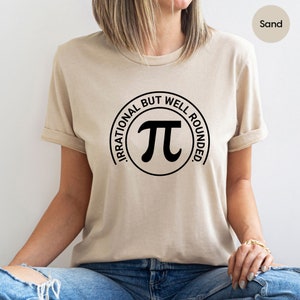 May include: A beige t-shirt with a black circle graphic that says "Irrational but well rounded" and has a pi symbol inside the circle.