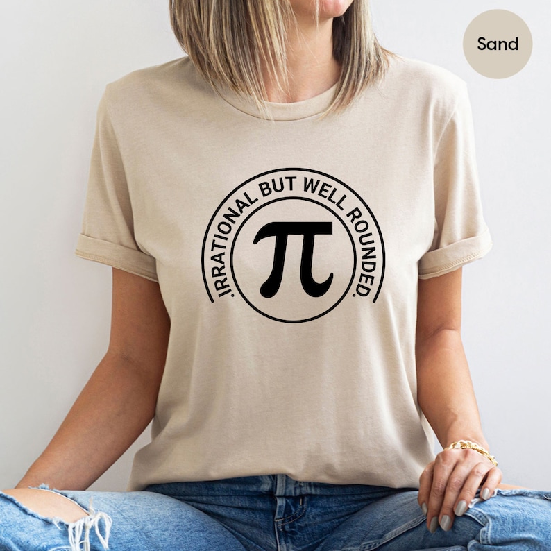 May include: A beige t-shirt with a black circle graphic that says "Irrational but well rounded" and has a pi symbol inside the circle.