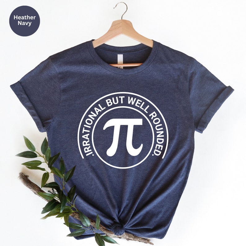 May include: A heather navy blue t-shirt with a white circle graphic that says "Irrational But Well Rounded" and has a white pi symbol inside the circle.