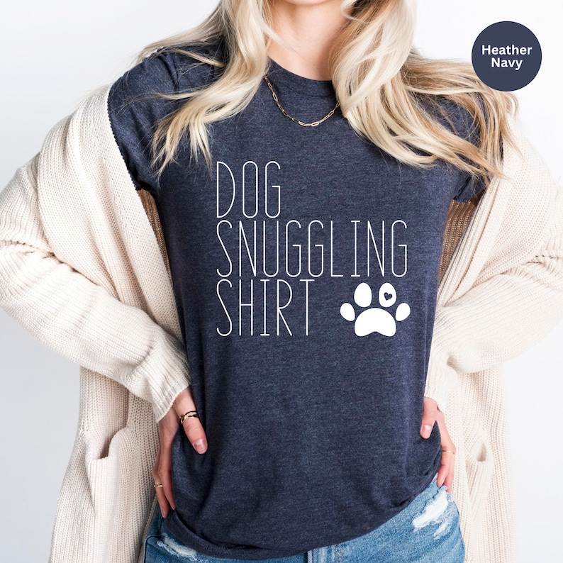 May include: A heather navy blue t-shirt with the text "DOG SNUGGLING SHIRT" and a white paw print with a small heart in the center.
