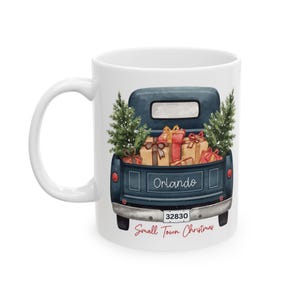 May include: White ceramic mug featuring a watercolor illustration of a blue pickup truck filled with wrapped gifts and Christmas trees. The truck has the word "Orlando" and the zip code "32830" on it. The text "Small Town Christmas" is below the truck.