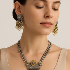 Puede incluir: Juego de joyas de estilo antiguo con collar y pendientes. El collar tiene un colgante con un diseño floral y perlas colgantes. Los pendientes reflejan el diseño del collar, con una parte superior floral y gotas de perlas. El metal tiene un acabado plateado y dorado.