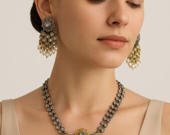 May include: Antique-style jewelry set featuring a necklace and earrings. The necklace has a pendant with a floral design and dangling pearls. The earrings mirror the necklace's design, with a floral top and pearl drops. The metal has a silver and gold finish.