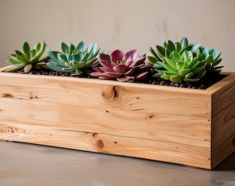 Op de afbeelding: Een rechthoekige houten plantenbak gevuld met verschillende vetplanten. De vetplanten zijn in verschillende tinten groen en paars. De plantenbak is gemaakt van lichtgekleurd hout met zichtbare nerf.